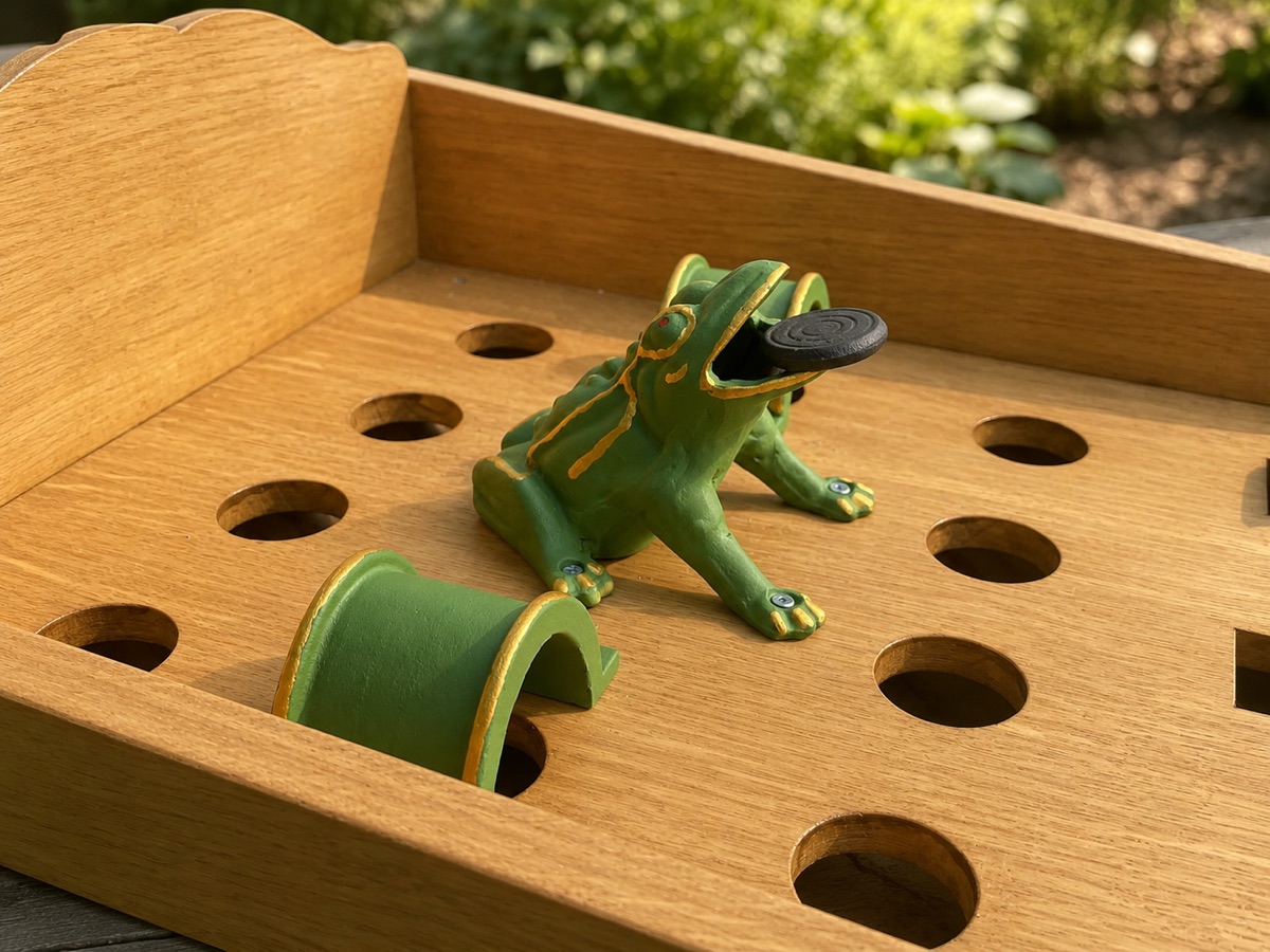 La grenouille en fonte verte du jeu de la grenouille, un palet en plein vol vers sa gueule