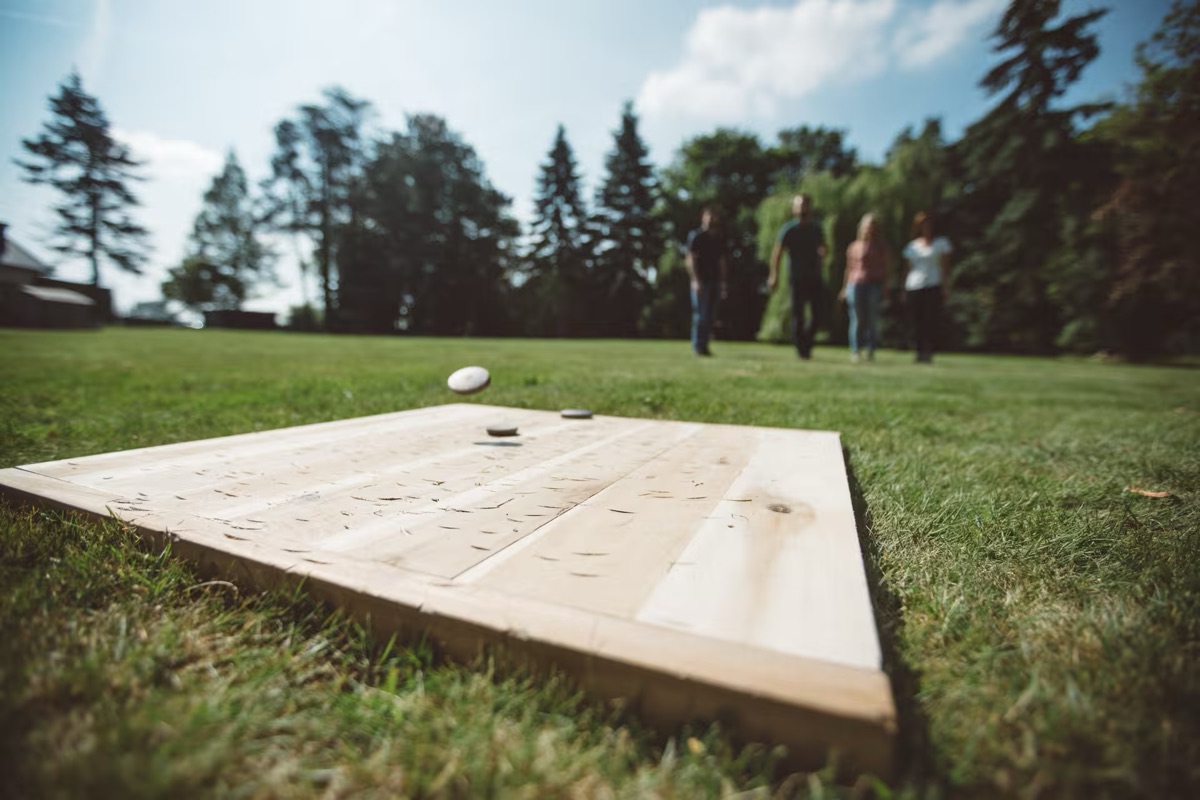 Planche de palet breton posée dans l'herbe, un palet en vol au-dessus du maître